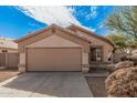 Tan house with a two-car garage and landscaping at 11465 W Virginia Ave, Avondale, AZ 85392