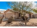 Tan house with a two-car garage and rock landscaping at 11465 W Virginia Ave, Avondale, AZ 85392