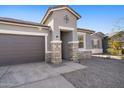 Home exterior featuring gray colors, a large driveway, and stone pillar accents at 24134 N Cotton Cir, Florence, AZ 85132