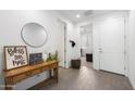 Inviting entryway with wood-look floors, decorative table, round mirror, and neutral wall color at 11517 E Unity Ave, Mesa, AZ 85212