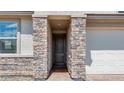 Close up of the front door with beautiful stone features surrounding the entrance at 9054 S 169Th Dr, Goodyear, AZ 85338