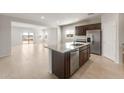 Open kitchen with an island, stainless appliances, dark wood cabinets, and tile flooring at 17875 W Getty Dr, Goodyear, AZ 85338