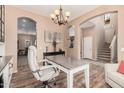 Bright office featuring built-in shelving, hardwood floors, natural light, and a modern chandelier at 21134 W Sunrise Ln, Buckeye, AZ 85396
