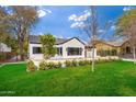 Charming home with manicured lawn, white brick exterior, black shutters and blooming white flower bushes at 412 W Vermont W Ave, Phoenix, AZ 85013