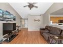 Comfortable living room featuring wood floors, large TV, and an open layout into the kitchen area at 8418 W Almeria Rd, Phoenix, AZ 85037