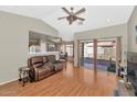 Open-concept living room with wood floors, ceiling fan, and sliding glass door to the backyard patio at 8418 W Almeria Rd, Phoenix, AZ 85037