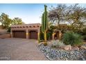Exterior shot of property, featuring large garage with adobe accents and desert landscaping at dusk at 1084 N Boulder Dr, Carefree, AZ 85377