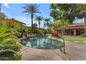 Inviting pool area with a rock waterfall feature and lush tropical landscaping at 11505 E Cochise Dr, Scottsdale, AZ 85259