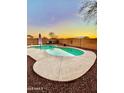 Backyard pool featuring a unique shape, desert landscaping, and brick perimeter wall at 1370 S 228Th Ln, Buckeye, AZ 85326
