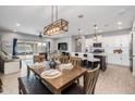 Open-concept dining area with wood table, seating for six, and modern chandelier at 1437 W Smoke Tree Ave, San Tan Valley, AZ 85140