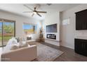 Bright living room with a cozy fireplace, ceiling fan, and sliding glass doors to the outside at 18509 W Galveston St, Goodyear, AZ 85338