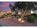 Inviting front yard featuring desert landscaping, mature trees, landscape lighting and stone accents at 13655 W Junipero Dr, Sun City West, AZ 85375