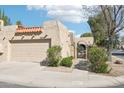 Inviting home exterior boasts a two-car garage and gated front patio, showcasing desert landscaping and an arched gate at 16447 N 29Th Ln, Phoenix, AZ 85053