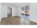 Bright living room with hardwood floors, a sliding glass door leading to the backyard, and fresh white paint at 5738 E Cicero Rd, Mesa, AZ 85205