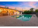 Backyard with covered patio, a large, sparkling pool, and serene evening ambiance at 7028 N 12Th Way, Phoenix, AZ 85020