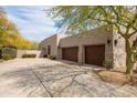 Spacious three-car garage with dark wood doors and desert landscaping at 9626 E Peak View Rd, Scottsdale, AZ 85262