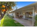 Covered patio with seating area, overlooking lush green lawn and mature orange tree at 12814 W Shadow Hills Dr, Sun City West, AZ 85375