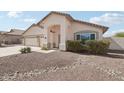 Tan single-story home featuring a two-car garage, desert landscaping, and a welcoming front entrance at 20626 N 55Th Ave, Glendale, AZ 85308