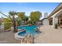 A gorgeous in-ground pool with a hot tub, rock feature, and mature landscaping provides a backyard oasis at 4914 N Valley Gln, Litchfield Park, AZ 85340