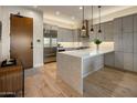 Sleek kitchen with stainless steel appliances and a large quartz island, pendant lights, and hardwood flooring at 6166 N Scottsdale Rd # A3001, Paradise Valley, AZ 85253