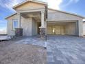Exterior of a new home featuring stone accents on the porch columns and a spacious, unfinished paver driveway at 9521 W Luxton Ln, Tolleson, AZ 85353