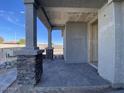 Covered porch with stone-accented columns and gray pavers, leading to the entrance of a new home at 9521 W Luxton Ln, Tolleson, AZ 85353