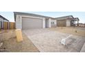 Single-story home with gray driveway leading to two car garage and desert landscaping at 9529 W Luxton Ln, Tolleson, AZ 85353