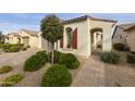 Lovely single-story home with an arched entry, neatly trimmed landscaping, and a paver walkway at 10312 E Tupelo Ave, Mesa, AZ 85212