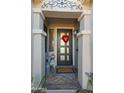 Close-up of a welcoming front porch featuring decorative columns, patterned tile, and a modern front door with a heart-shaped wreath at 22805 W Hopi St, Buckeye, AZ 85326