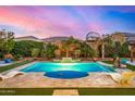 Beautiful backyard pool with elegant landscaping and a serene atmosphere under a colorful evening sky at 3005 E Valencia Dr, Phoenix, AZ 85042