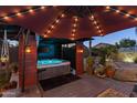 Relaxing hot tub in a custom wood enclosure with lighting and outdoor decor at 586 E Stirrup Ln, San Tan Valley, AZ 85143