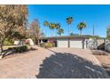 Stunning home exterior featuring a brick driveway and desert landscaping with lush green trees at 9821 N 29Th Pl, Phoenix, AZ 85028