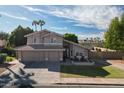 A two-story home with a well-maintained lawn, two chairs on the front porch, and palm trees in the distance at 1320 N Desoto St, Chandler, AZ 85224