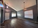 Open living room features hardwood floors, neutral paint, two chandeliers, and two windows at 3229 S 93Rd Ave, Tolleson, AZ 85353