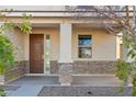 Covered front porch with stone accents, a brown front door, and side panel window at 37292 N Yellowstone Dr, San Tan Valley, AZ 85140