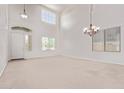 Spacious living room featuring soaring ceilings, large windows, and elegant chandelier at 42735 W Bravo Dr, Maricopa, AZ 85138