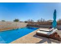 Backyard pool with lounge chairs, an umbrella, and desert landscaping at 5345 W Leodra Ln, Laveen, AZ 85339
