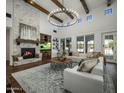 Spacious living room featuring a stone fireplace, beamed ceilings, large windows and a large chandelier at 9412 E Hidden Spur Trl, Scottsdale, AZ 85255
