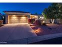 Charming home with a large garage, desert landscaping, and warm lighting at dusk at 12936 W Sola Dr, Sun City West, AZ 85375