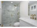 Bright, newly remodeled bathroom featuring a glass shower with gold fixtures and a modern vanity at 13446 N 18Th Ave, Phoenix, AZ 85029