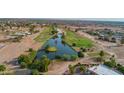 Aerial view showcasing neighborhood pond with a small island and palm tree surrounded by mature landscaping at 14264 S Baniff Ln, Arizona City, AZ 85123