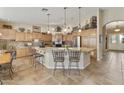 Bright eat-in kitchen featuring a large island with seating, custom cabinets, modern stainless appliances, and a tile backsplash at 23731 S Angora Dr, Sun Lakes, AZ 85248