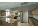 Spacious kitchen featuring stainless steel appliances, wood cabinets, granite counters, and a breakfast bar at 2902 E Escondido Ave, Mesa, AZ 85204