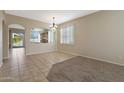 Spacious dining room features tile flooring, decorative chandelier, and arched entryway to kitchen at 6516 W Matilda Ln, Glendale, AZ 85308