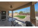 Covered back patio with dining table and chairs overlooking the manicured backyard at 29903 N 127Th Ave, Peoria, AZ 85383