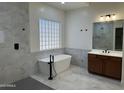 Bright bathroom with a soaking tub, glass block window, vanity, modern fixtures, and marble-look tile at 3010 E Cedar Dr, Chandler, AZ 85249