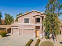 Two-story home featuring a three-car garage, neutral stucco and tile roof with manicured shrubs along the walkway at 30263 N Bobcat Way, San Tan Valley, AZ 85143