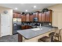 Well-equipped kitchen featuring dark wood cabinets, stainless steel appliances, breakfast bar and tiled backsplash at 42072 W Dorsey Dr, Maricopa, AZ 85138