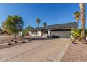 Single-story home featuring a two-car garage, desert landscaping, and mature palm trees on a sunny day at 520 E Jahns Pl, Casa Grande, AZ 85122