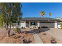 Charming single-story home featuring a two-car garage, desert landscaping, and mature palm trees on a sunny day at 520 E Jahns Pl, Casa Grande, AZ 85122